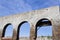 Old wall with three open archways that once held windows, abandoned building ruins