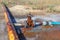 Old water valve. An rusty water valve in a puddle of flowing water. Large and rusty faulty leaking valve in close-up of an outdoor