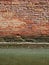 An old weathered brick wall above the canal water line in Venice