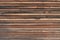 Old, weathered, brown wood planking of a facade with narrow wooden strips