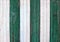 Old weathered colored wooden wall made of vertical stripes, with green and white peeled paint.