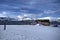 Old weathered and damaged barn on frosty snowy field with blue fjord and sky backdrop with mighty mountain peaks in the arctic cir