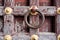 Old, weathered doorknocker ring handle on an ancient wooden door with peeling paint