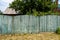 The old weathered wooden green fence near residential homes