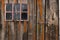 Old weathered and worn wooden planks with door and pink framed window