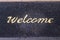 Old wet doormat with the word welcome