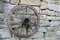 An old wheel of a waggon hanging on a wall made of stones