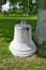 Old white bell on the grass in the church park