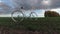 Old white bicycle on field and clouds, time lapse