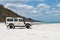 Old white coloured four-wheel drive off-road vehicle standing on a beach on the west coast of Fraser Island, Queensland.