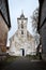 Old white countryside church with tower near small houses in old countryside city