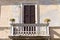 Old white decorated balcony with two plants and flowers of a ruined ancient house Italy, Europe