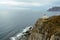 Old white lighthouse on a steep precipitous place around the blue clear ocean, navigation of sea routes