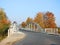 Old white metallic bridge, road and colorful trees, Lithuania
