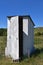 Old white outhouse with partially open door