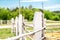 Old white painted zigzag wooden fence at ranch or horse farm with green forest and blue sky on background. Rural