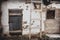 Old white wall of a house with peeling paint and an old closed door. Decrepit building