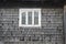 Old white window on the wall of Hutsul traditional house with wooden scales