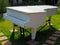 An old white wooden grand piano stands on a green lawn in the park. Park decor