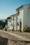 Old whitewashed houses and flowered shrubs in cobblestone alley