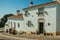 Old whitewashed houses and flowered shrubs in cobblestone alley