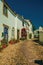 Old whitewashed houses and flowered shrubs in cobblestone alley