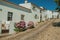 Old whitewashed houses and flowered shrubs in cobblestone alley