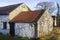 An old whitewashed stone built Irish Cottage with a small annex roofed with bangor Blue roofing tiles and rusting corrugated tin s