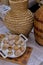 An old wicker wine jug stands next to a set of seashells.