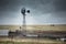 Old windmill in the farmland with cattle in the back on a cloudy day