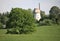 Old windmill between green trees on a hillside in Latvia on a sunny May day 2019