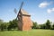 Old windmill on a hill in the rays of the sun at sunset, green fields. Spring rural landscape with an old mill. Stary Podvorov, So