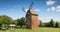 Old windmill on a hill in the rays of the sun at sunset, green fields. Spring rural landscape with an old mill. Stary Podvorov, So