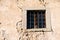 Old window with bars in decayed stone wall