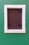 Old window with brown shutters on green wall