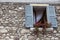 Old window with open shutters with flowers on the window sill on the stone wall. Italian Village