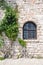 Old window with plant in ancient gray stone wall