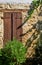 Old window with wooden closed shutters in the stone house wall. Lania village.  Limassol