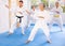 Old woman attendee of karate classes practicing kata standing in row with others