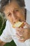 An old woman is biting a dried toast