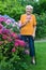 Old Woman with Cane Holding Flowers at the Garden