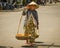 Old woman carries a heavy load of fruit in Hoi An, Vietnam