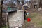 An old woman in a deserted village is gathering water from a well in a bucket, living alone