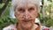 Old woman in eyeglasses looking into camera and smiling outdoor. Portrait of happy granny in glasses spending time