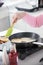 An old woman frying pancakes and turning the pancakes over using a silicone paddle