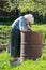 Old woman in the garden at an iron barrel