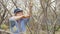 Old woman gardener sawing tree branches while spring garden works