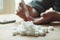 Old woman hands using lancet on finger to check blood sugar level, glucometer and sugar cubes on wooden table close up, diabetes