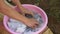 Old woman hands washing clothes in a pink plastic bowl