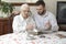 Old woman with her grandson sitting at the table in the living room and watching old photos.